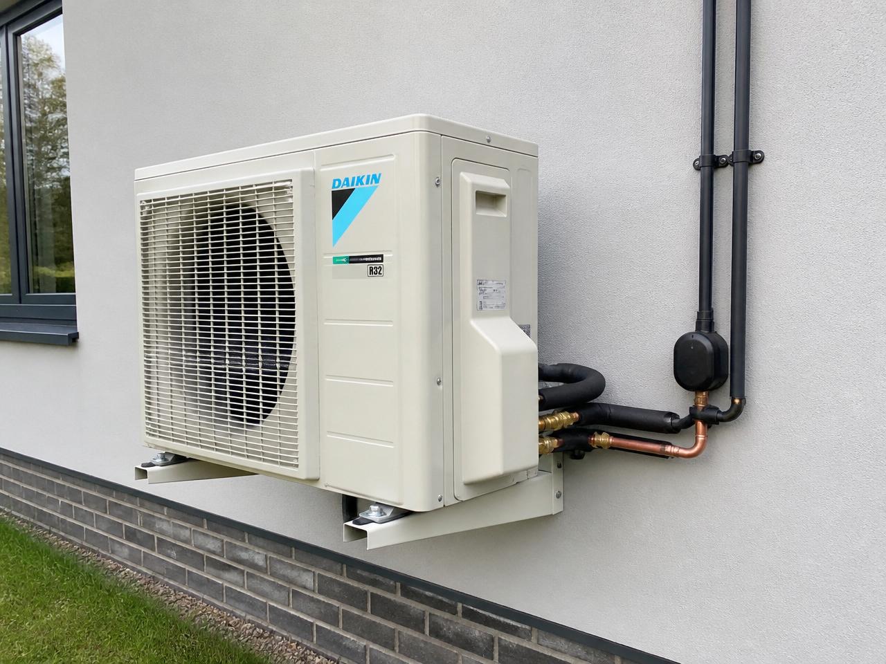 Outdoor air conditioning condenser unit installed on a UK brick exterior wall
